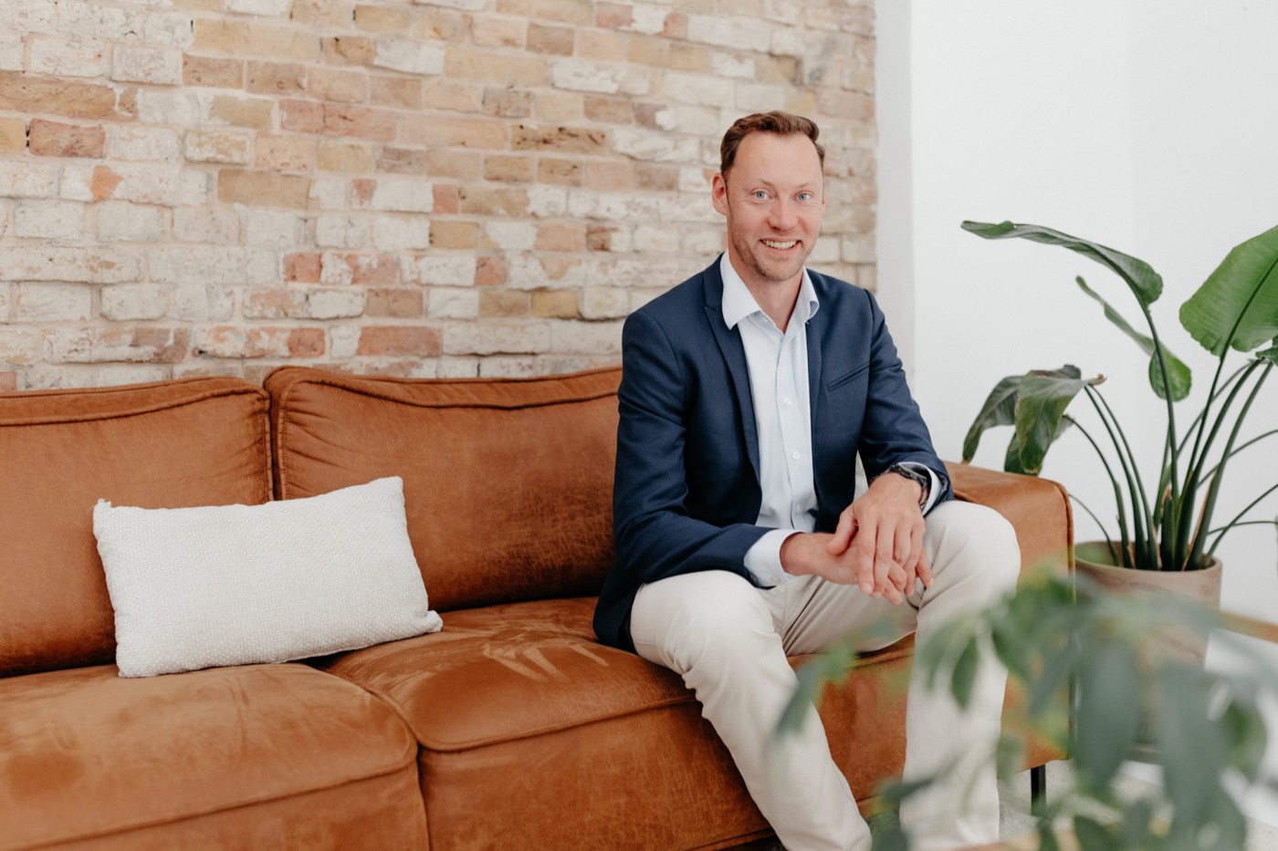 Philipp Schett sitting on a leather sofa in front of a brick wall